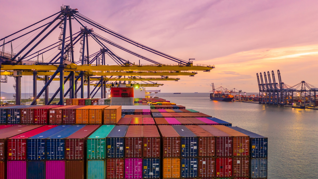 Container ship loading and unloading in deep sea port at sunset,