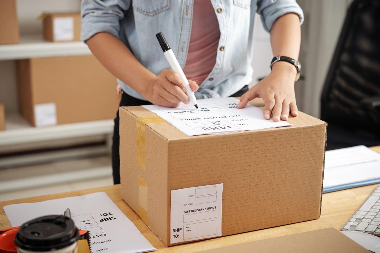 woman writing label on box