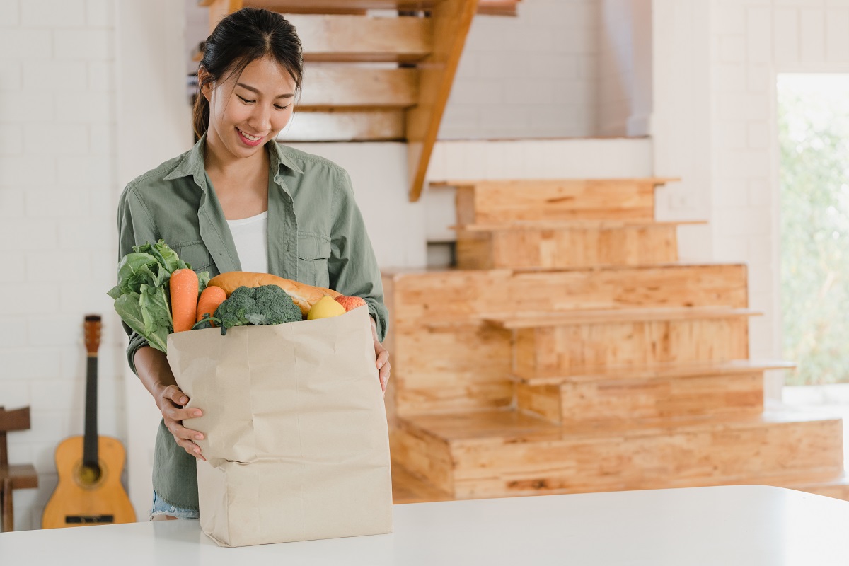 Asian women holding grocery shopping paper bags at home, young A