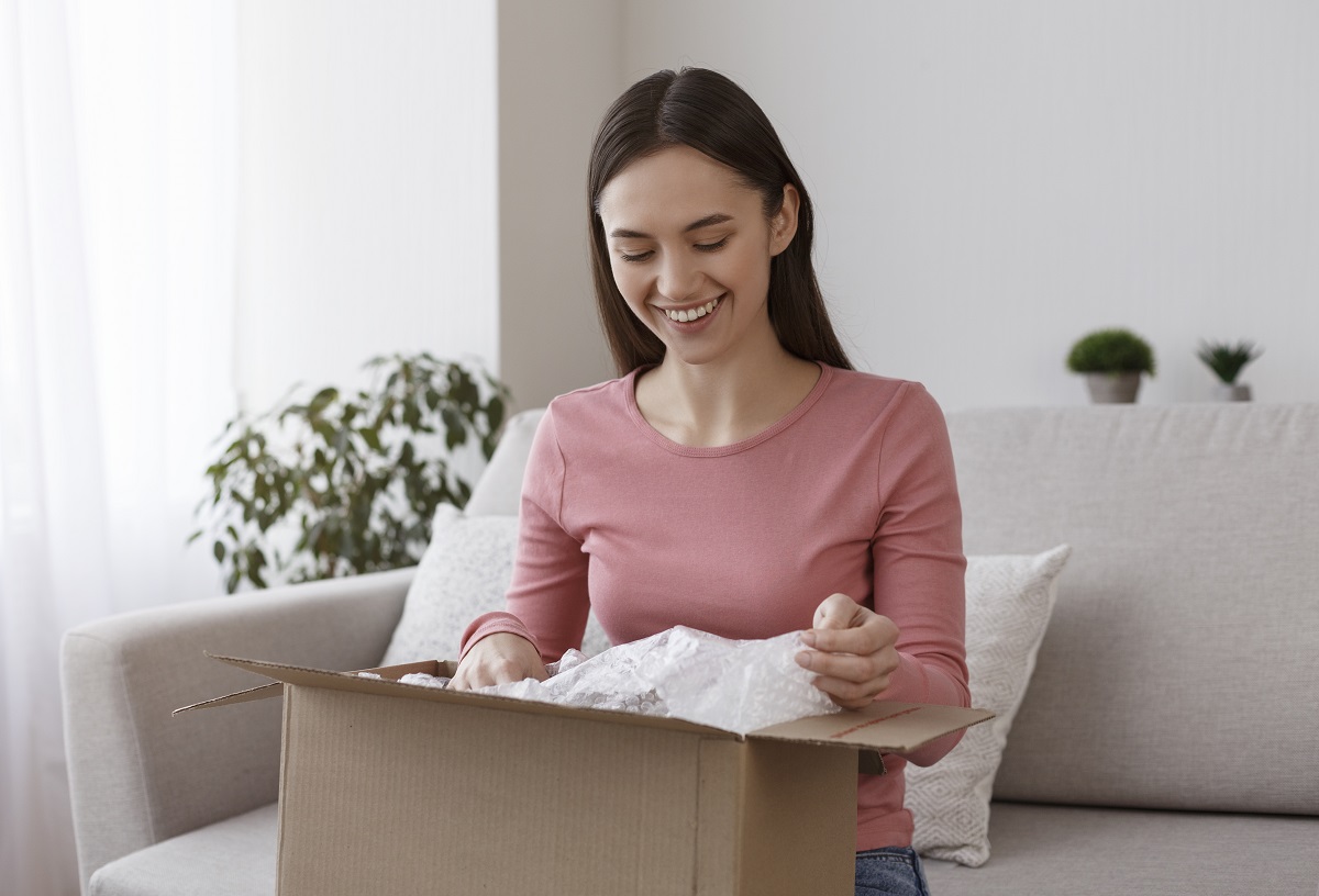 Happy young girl unboxing international package at home